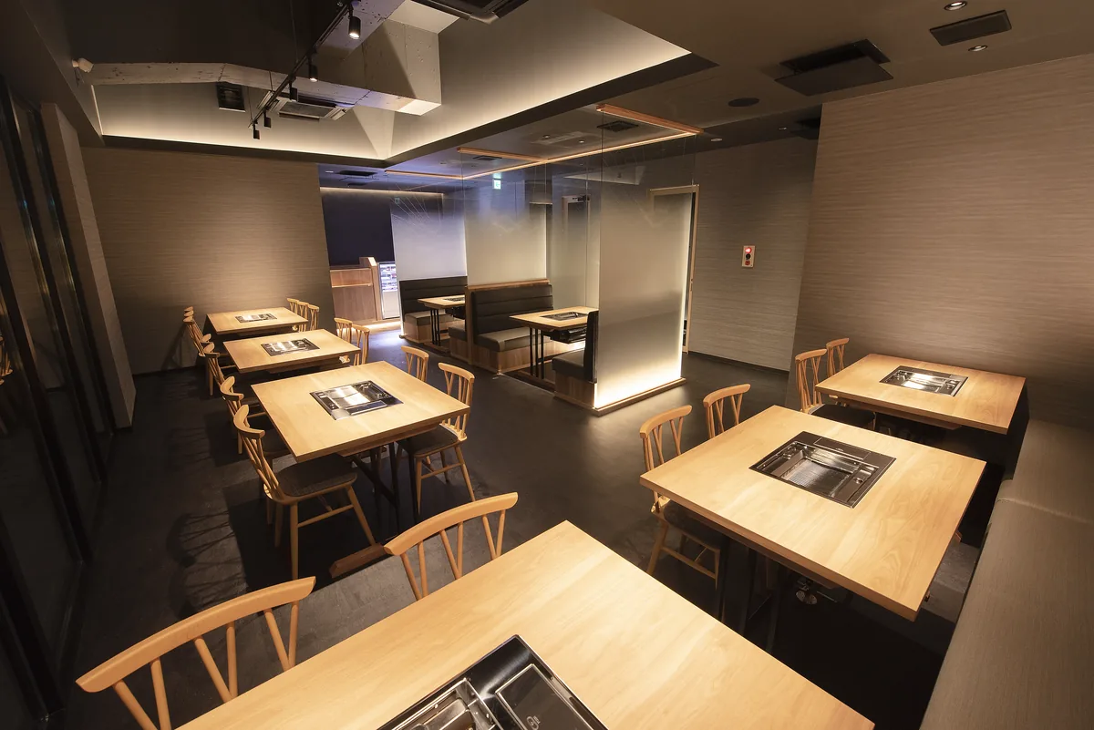 無煙グリル付きのテーブル席が並ぶ直営店の客席